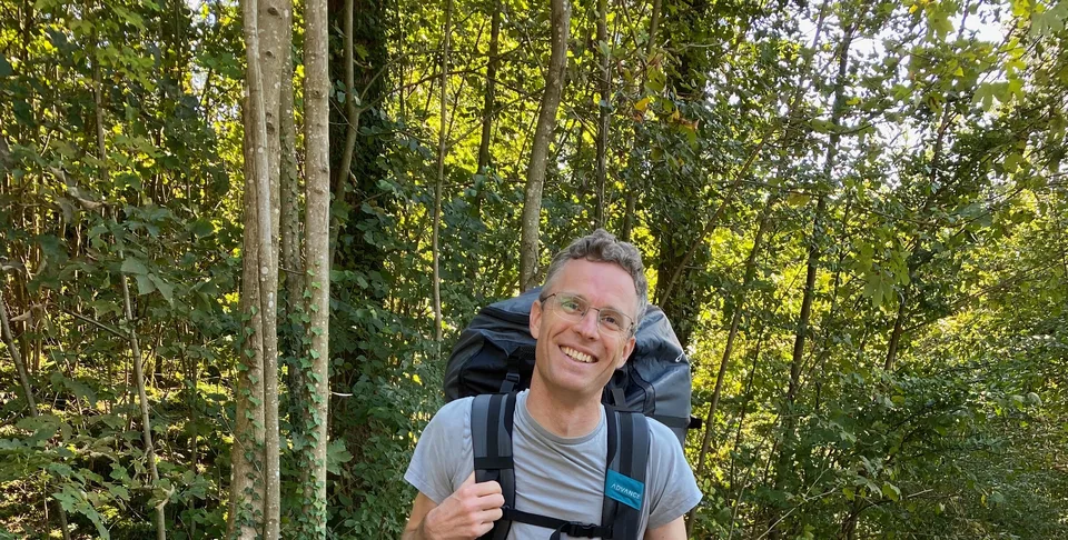 Martin and his son on a forest trail, both with backpacks